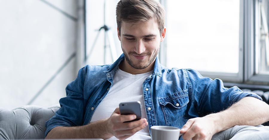 Young man using his mobile phone at home